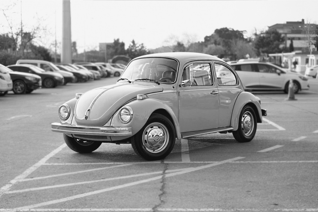 Black and white image of Volkswagen beetle in parking lot